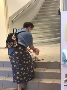 Frau hält Kleinkind, das eine Treppe hochklettert