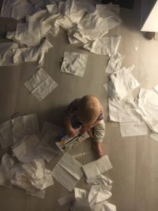 Kind sitzt inmitten von Taschentüchern am Boden 